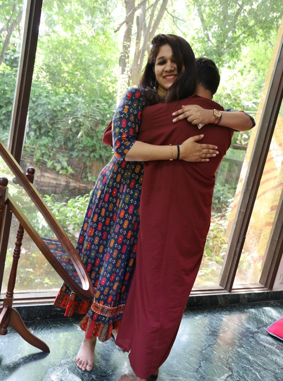 Two participants of a Happy Life Foundation workshop sharing a long hug in a sunlit room